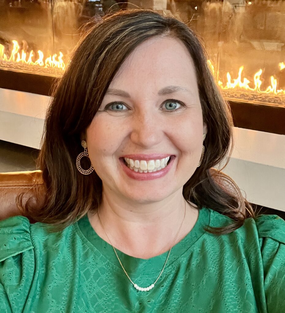 Jenny Cotten in a green shirt in front of a fireplace